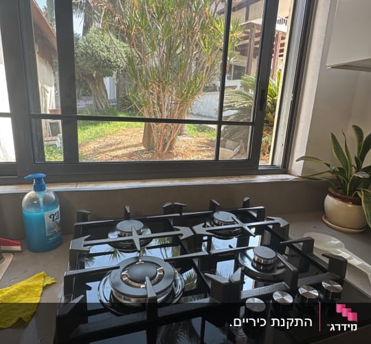 כיריים גז במטבח עם חלון פתוח ועצים בחוץ